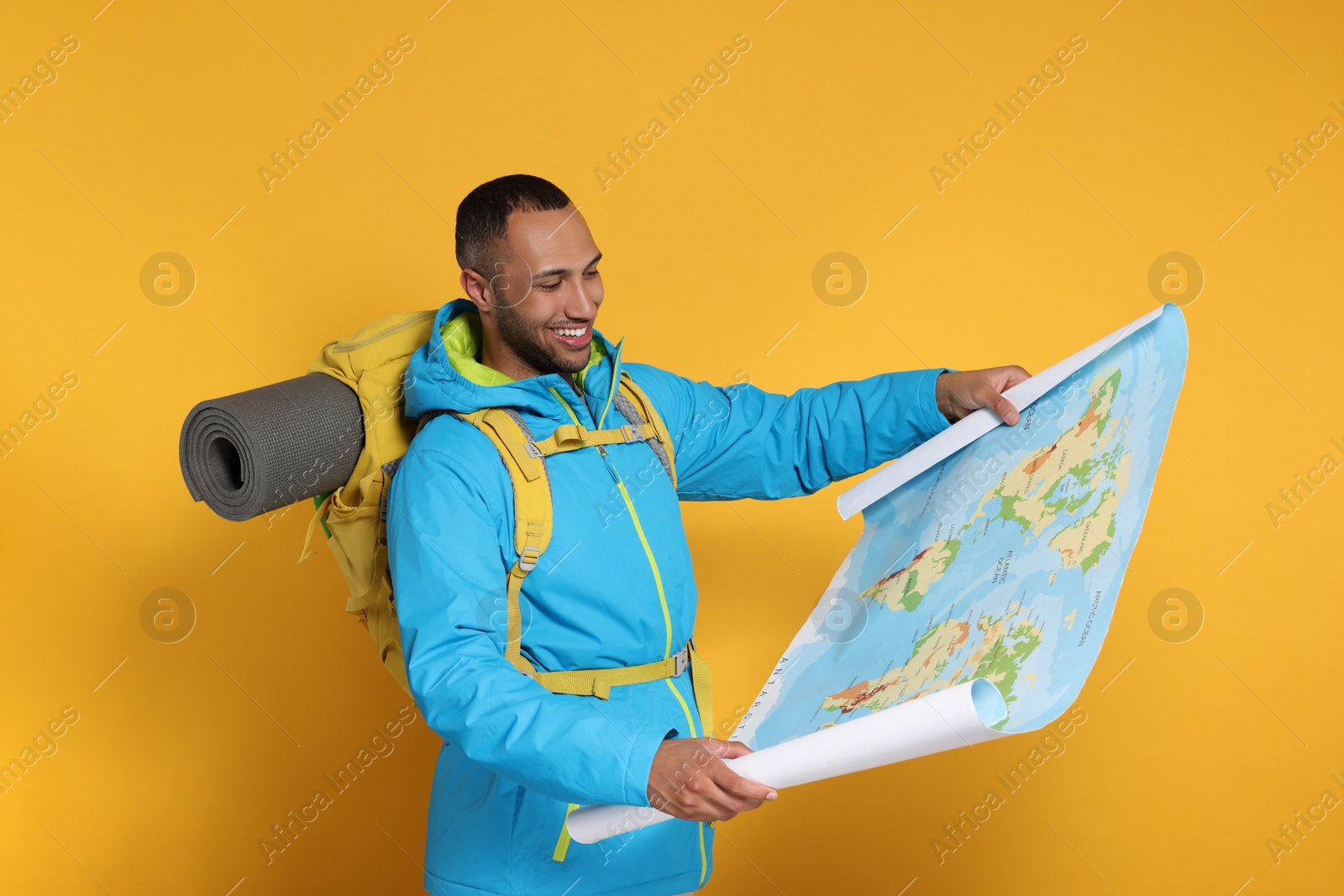 Photo of Happy tourist with backpack and map on yellow background