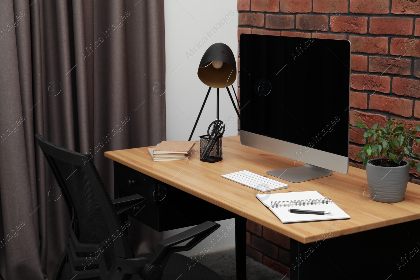 Photo of Cozy workplace with modern computer on desk and comfortable chair at home