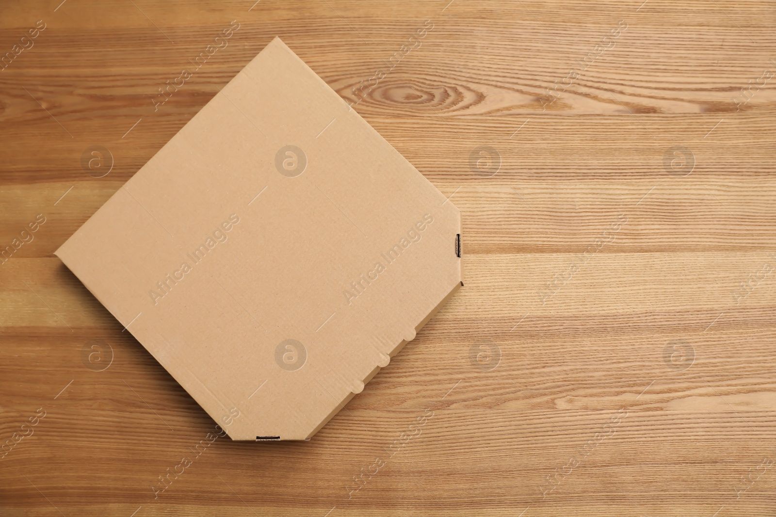 Photo of Cardboard pizza box on wooden background, top view. Mockup for design