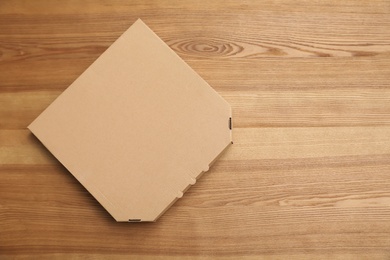 Photo of Cardboard pizza box on wooden background, top view. Mockup for design