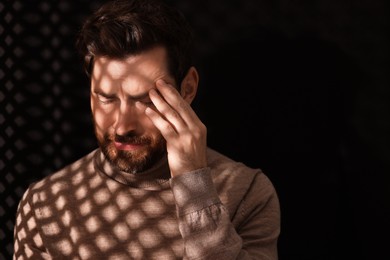 Upset man listening to priest during confession in booth, space for text