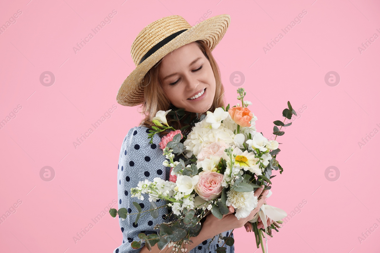 Photo of Beautiful woman in straw hat with bouquet of flowers on pink background