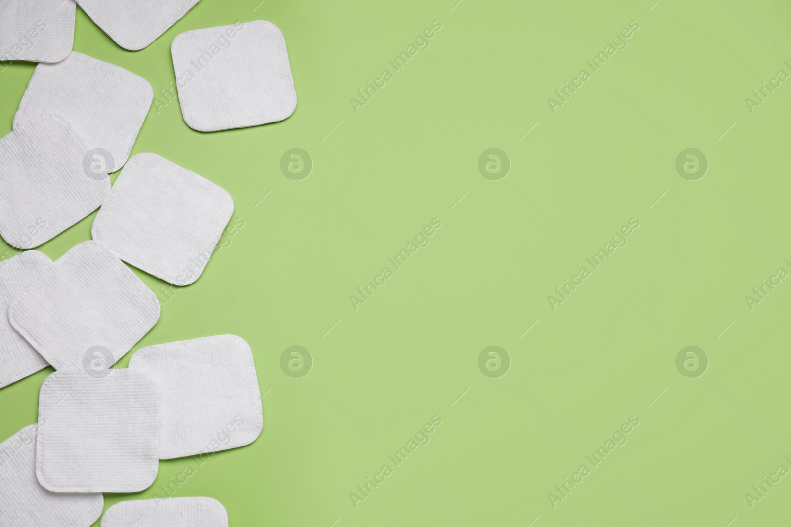 Photo of Many cotton pads on green background, flat lay. Space for text