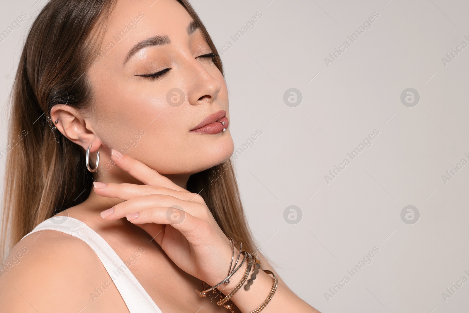 Photo of Young woman with lip and ear piercings on white background, space for text