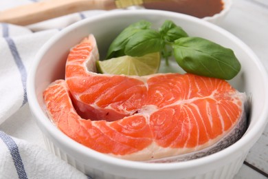 Fresh marinated fish and lime on white wooden table, closeup