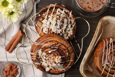 Photo of Delicious rolls with toppings and almond on wooden table, flat lay. Sweet buns