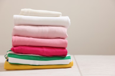 Photo of Stack of folded clothes on white table against grey background, space for text