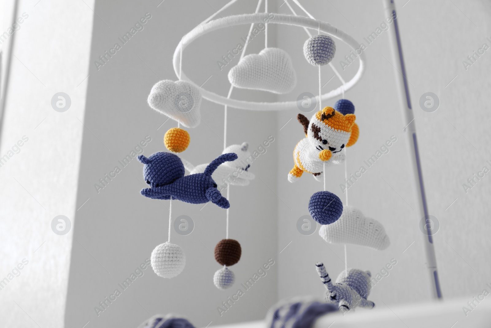 Photo of Modern baby crib mobile in children's room, low angle view