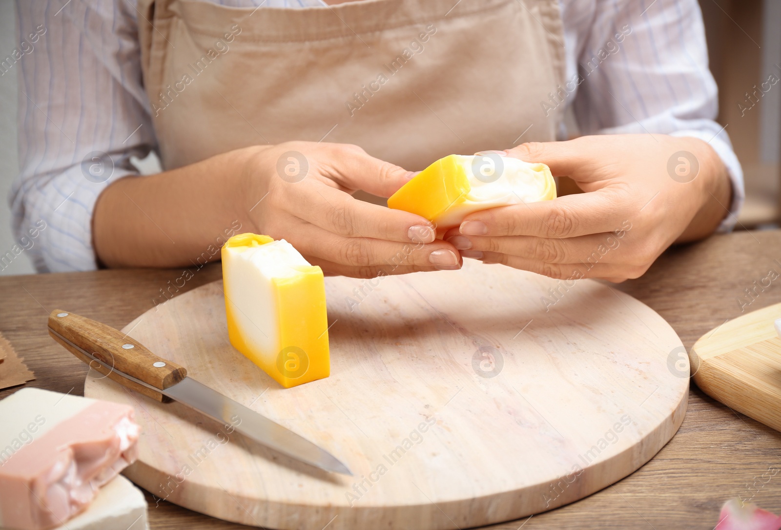 Photo of Woman holding natural handmade soap at wooden table, closeup