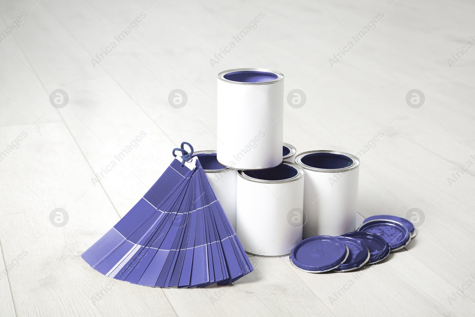 Image of Cans of violet paints and color palette samples on wooden floor indoors