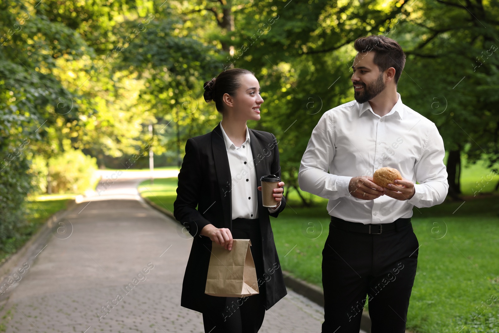 Photo of Business lunch. Happy colleagues spending time together during break in park