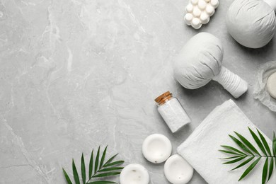 Photo of Flat lay composition with herbal massage bags and other spa products on grey marble table, space for text