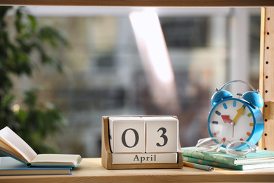 Wooden block calendar and alarm clock on shelf indoors