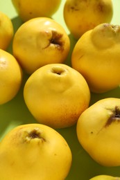 Photo of Tasty ripe quinces on light green background, closeup