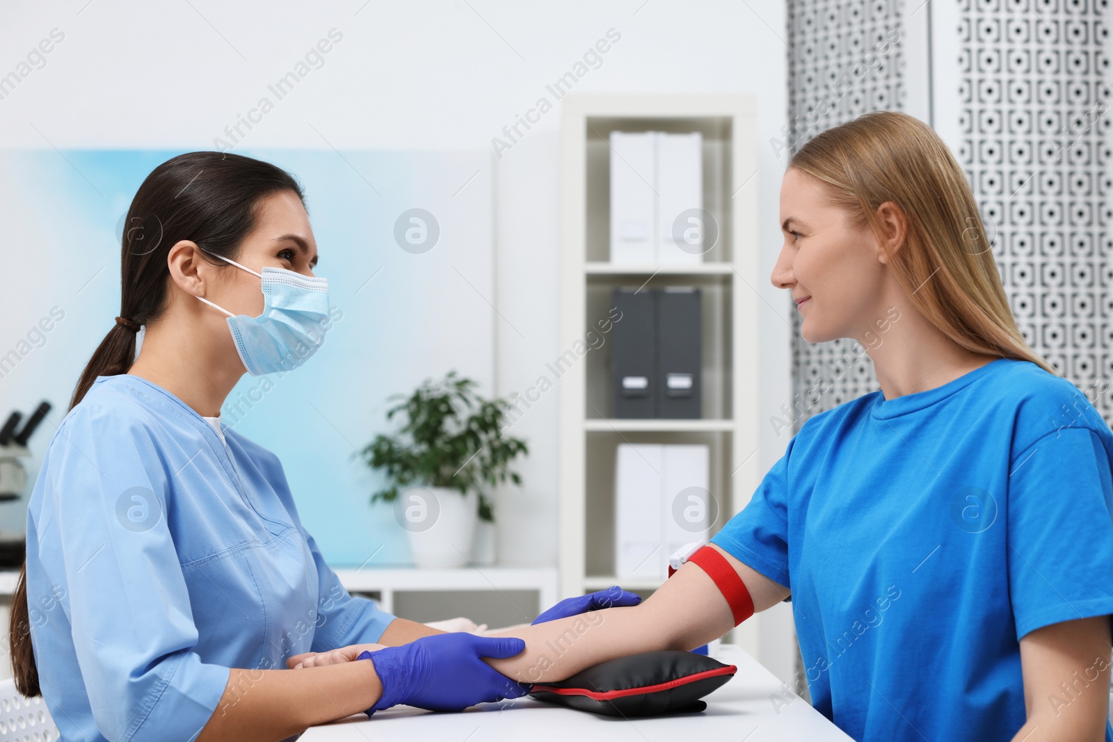 Photo of Laboratory testing. Doctor taking blood sample from patient at white table in hospital