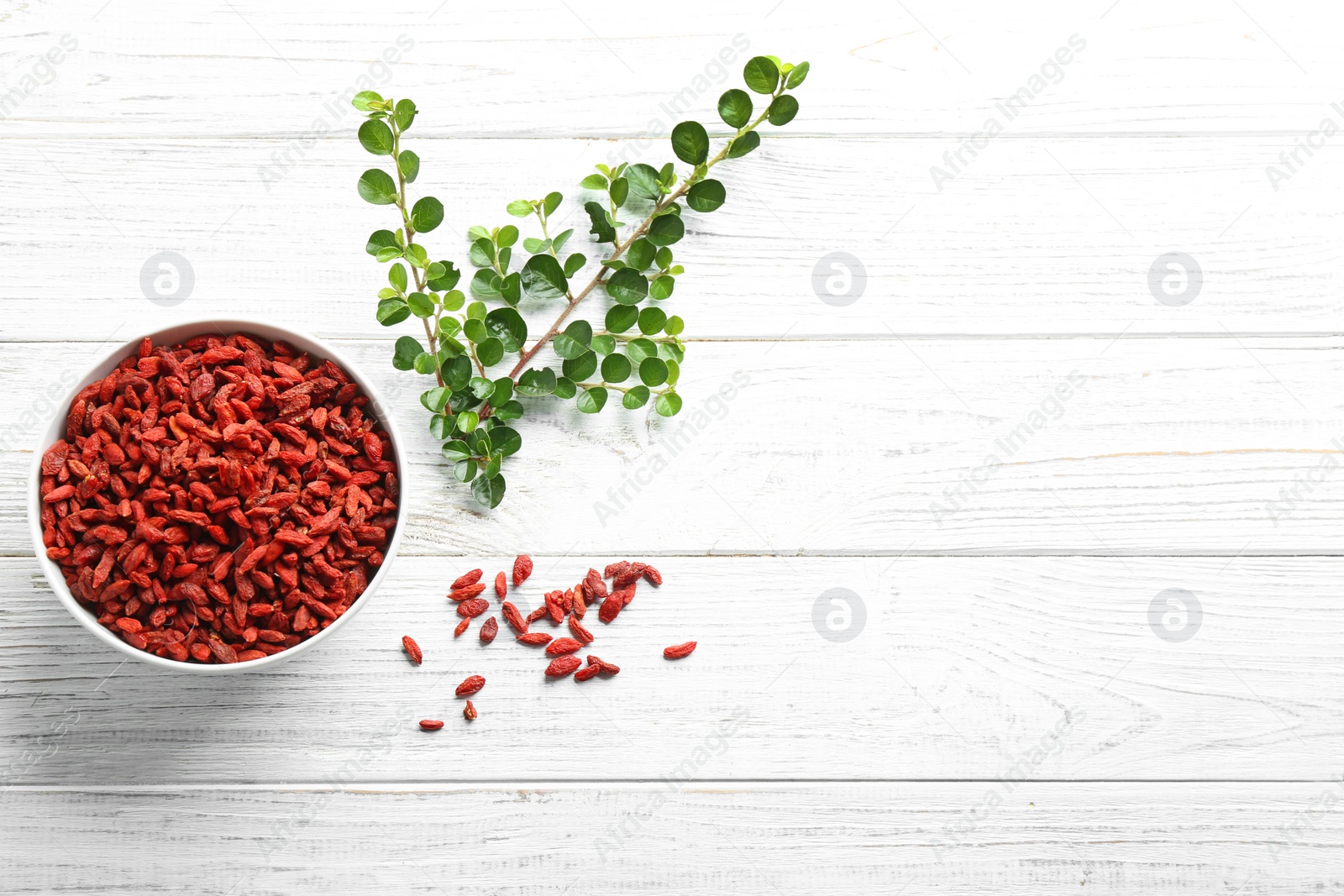 Photo of Flat lay composition with dried goji berries on white wooden table, space for text. Healthy superfood
