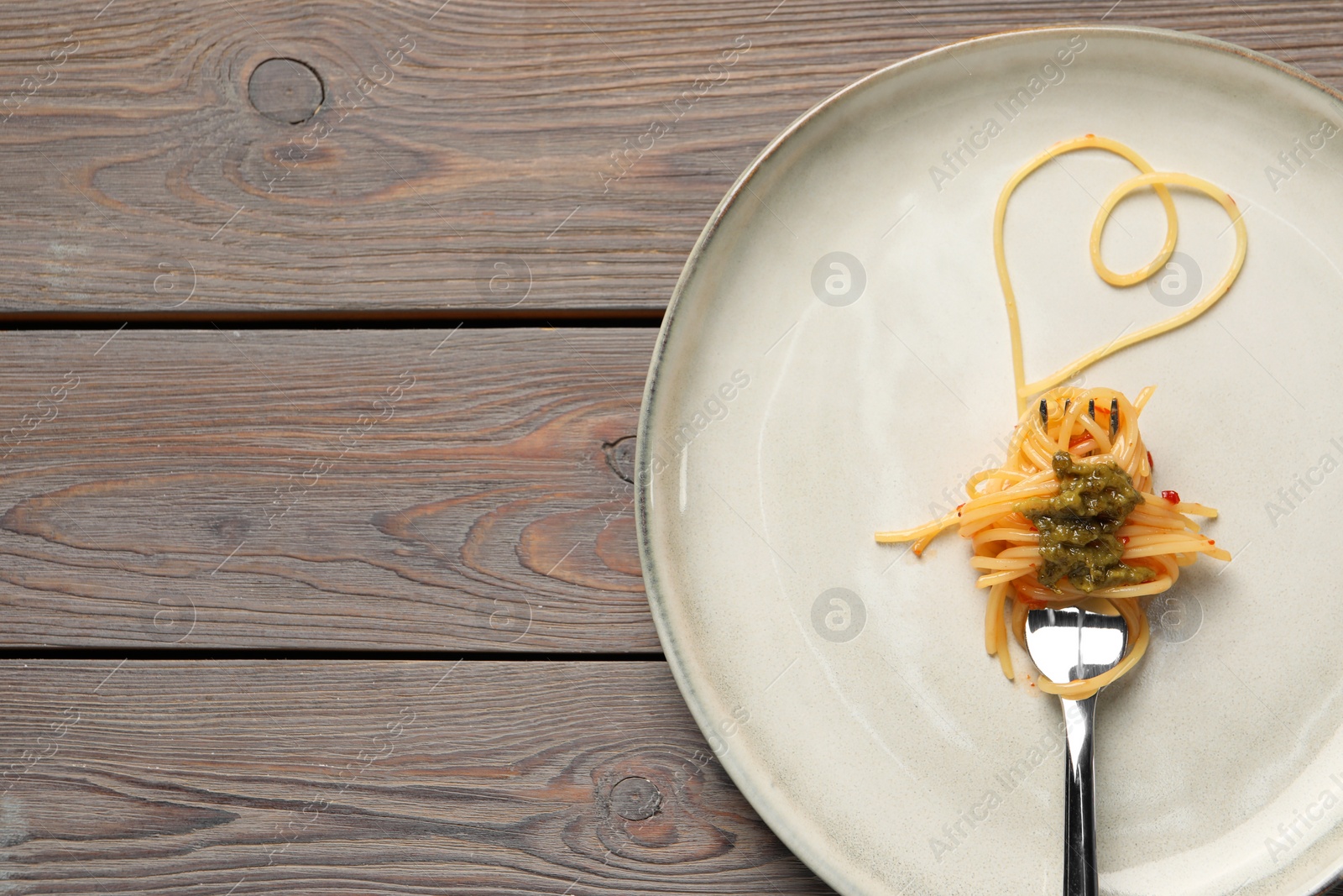 Photo of Heart made with spaghetti and fork on wooden table, top view. Space for text