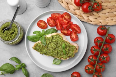 Delicious chicken breast with pesto sauce and tomatoes on light gray table, flat lay