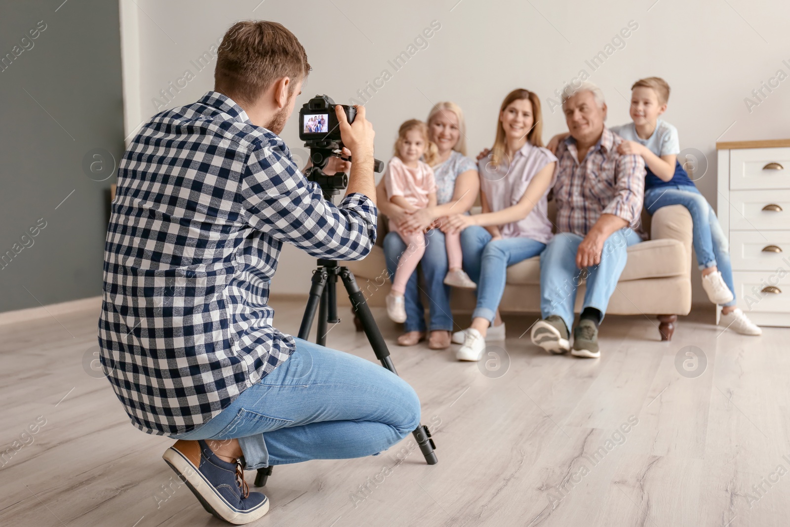 Photo of Professional photographer taking photo of family on sofa in studio