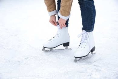 Photo of Woman lacing figure skate on ice rink, closeup