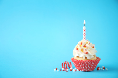 Photo of Delicious birthday cupcake with candle on light blue background. Space for text