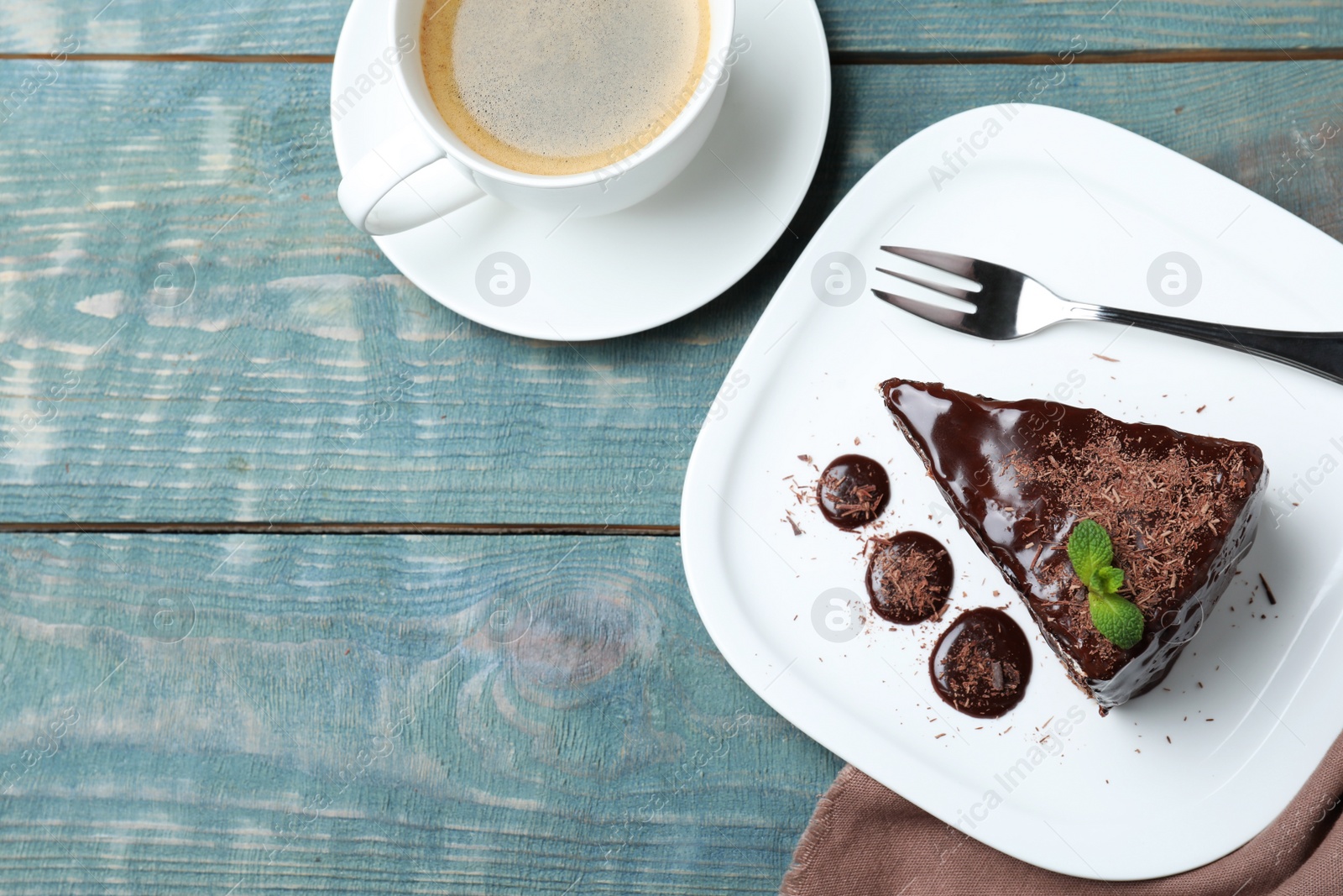 Photo of Delicious chocolate cake with mint on light blue wooden table, flat lay. Space for text