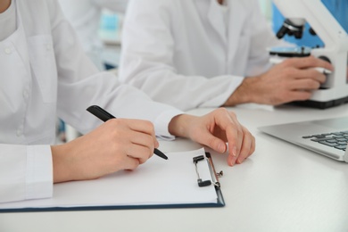 Photo of Medical student with clipboard working in scientific laboratory, closeup