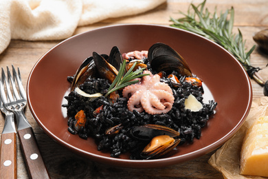 Delicious black risotto with seafood on wooden table