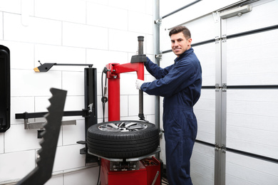 Man working with tire fitting machine at car service