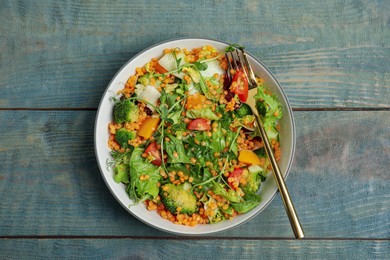 Delicious salad with lentils and vegetables on light blue wooden table, top view