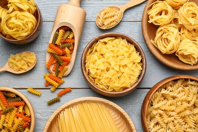 Photo of Different types of pasta on light grey wooden table, flat lay