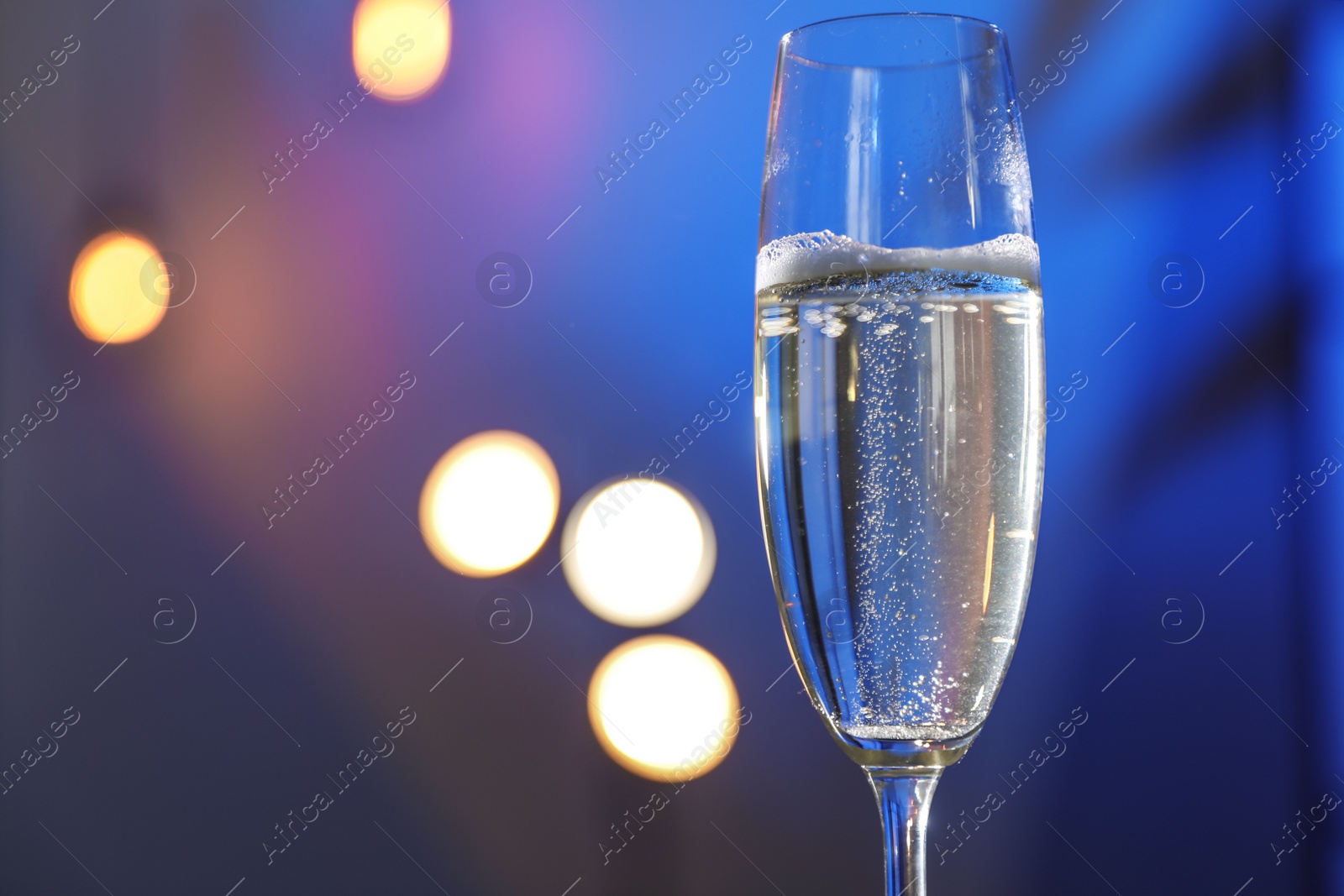 Photo of Glass of champagne on color background, closeup. Space for text