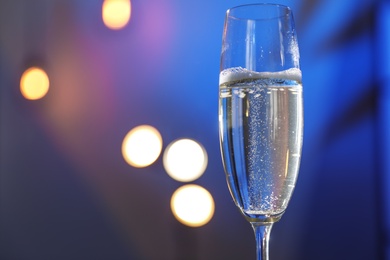 Glass of champagne on color background, closeup. Space for text