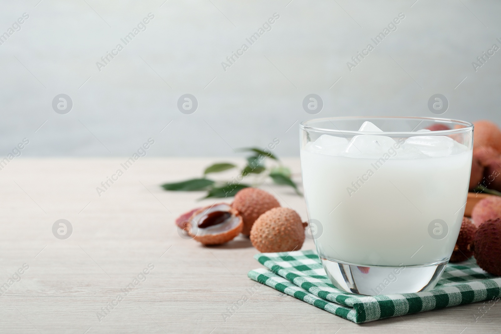 Photo of Fresh lychee juice on white wooden table. Space for text