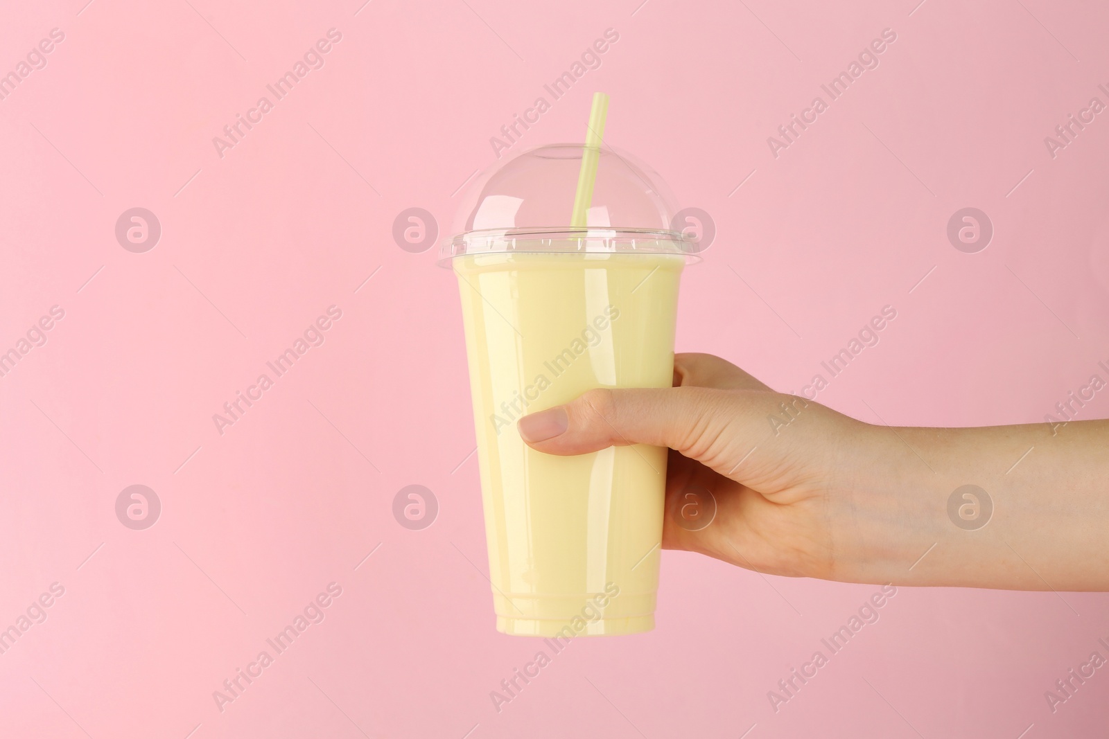 Photo of Woman holding plastic cup of tasty smoothie on pink background, closeup