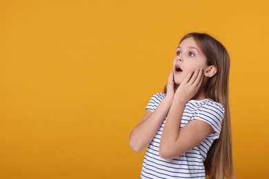 Portrait of surprised girl on yellow background. Space for text