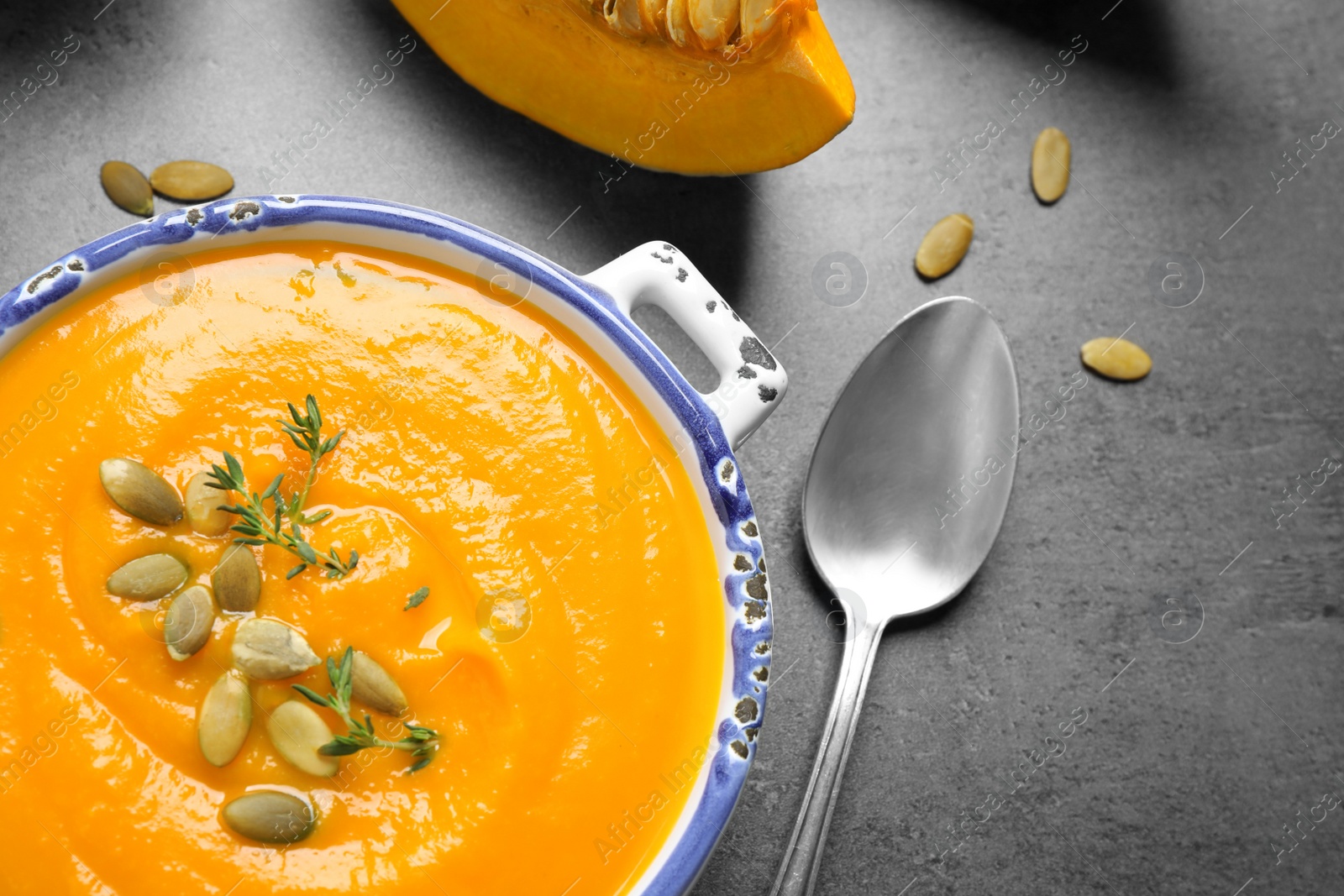 Photo of Delicious pumpkin soup in bowl on grey table, flat lay