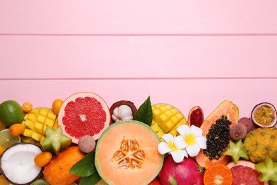 Photo of Different exotic fruits on light pink wooden background, flat lay. Space for text