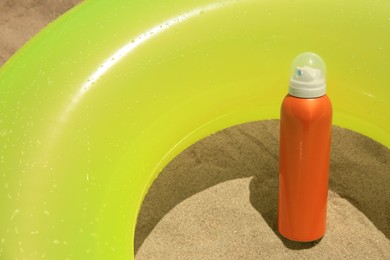 Photo of Sunscreen and inflatable ring on sand. Sun protection care