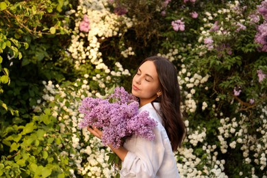 Photo of Attractive young woman with lilac flowers outdoors