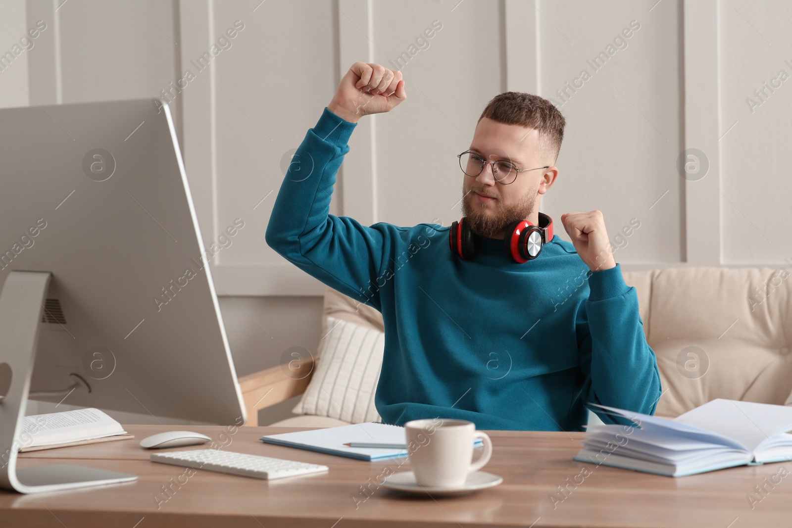 Photo of Online test. Happy man studying with computer at home