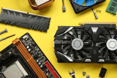 Photo of Graphics card and other computer hardware on yellow background, flat lay