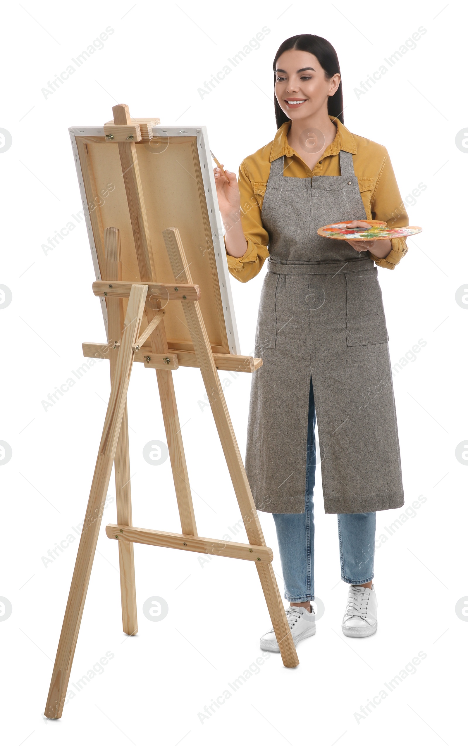 Photo of Young woman drawing on easel against white background