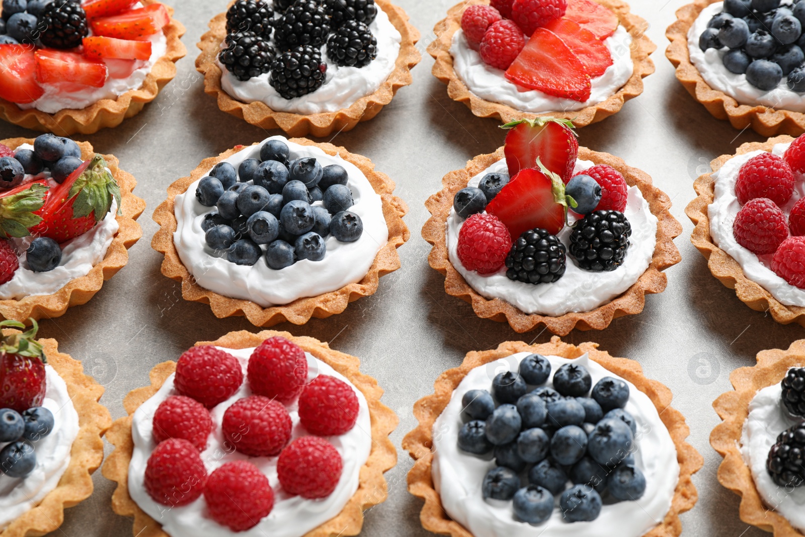 Photo of Many different berry tarts on table. Delicious pastries