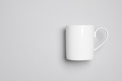 Photo of One white ceramic mug on light background, top view and space for text