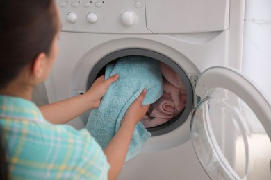 Photo of Woman putting dirty laundry into washing machine indoors, closeup