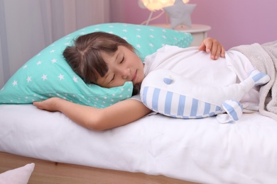 Little girl with toy sleeping in bed at home