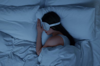 Photo of Woman with mask sleeping in bed at night, top view