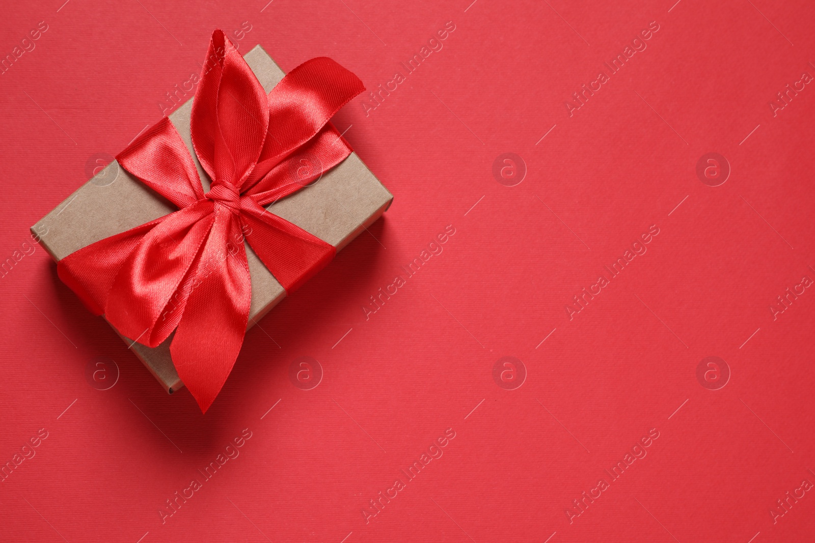 Photo of Beautiful gift box with bow on red background, top view. Space for text