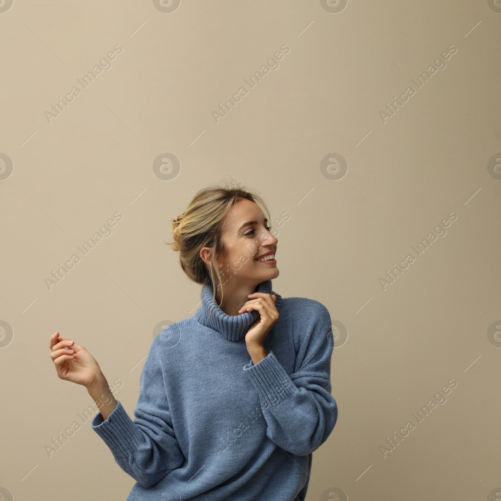 Photo of Beautiful young woman wearing knitted sweater on beige background